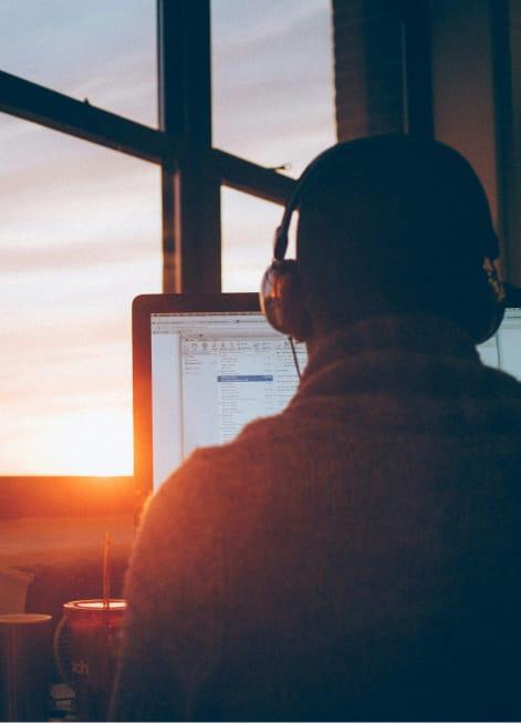 Photo of a person working from home with the sunset coming through the window.